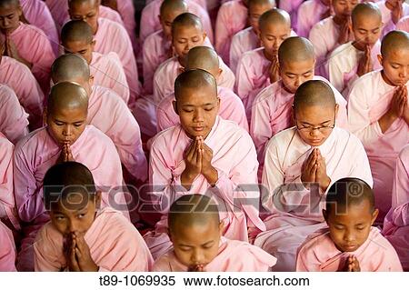 Stock Photography - young Buddhist nuns pray at the Shwedagon Golden Temple complex, the largest and most scared of all Buddhist sites in Myanmar.. Fotosearch