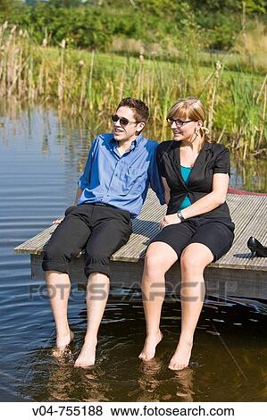 Young business couple sitting on a footbridge at a lake View Large Photo Image Stock Photo - Young business couple sitting on a footbridge at a lake. Fotosearch