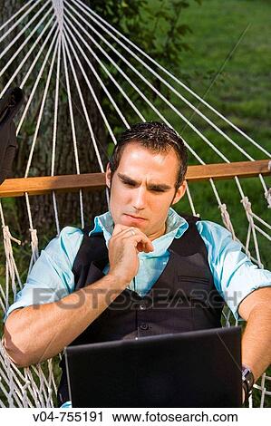 Young business man using a laptop computer in a hammock View Large Photo Image Stock Image - Young business man using a laptop computer in a hammock. Fotosearch