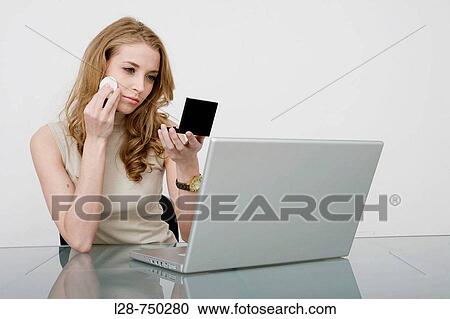 Young business woman applying make-up to face, portrait, close-up View Large Photo Image Stock Image - Young business woman applying make-up to face, portrait, close-up. Fotosearch