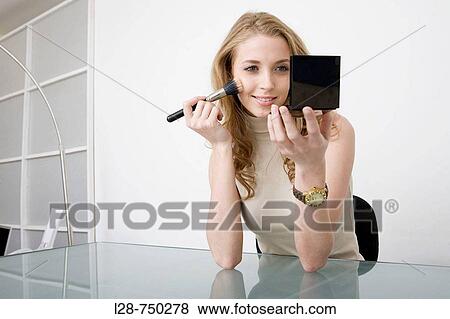 Young business woman applying make-up to face, portrait, close-up View Large Photo Image Stock Photo - Young business woman applying make-up to face, portrait, close-up. Fotosearch
