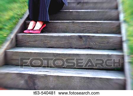 Stock Image - young business woman sitting on wooden stairway. Fotosearch