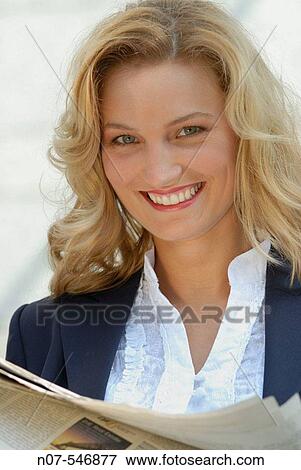 Young business woman smiling holding a financial newspaper. View Large Photo Image Stock Photo - Young business woman smiling holding a financial newspaper.. Fotosearch