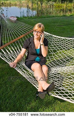 Young business woman using her cell phone in a hammock View Large Photo Image Stock Image - Young business woman using her cell phone in a hammock. Fotosearch