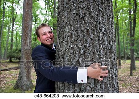Young businessman in forest hugging tree View Large Photo Image Stock Photo - Young businessman in forest hugging tree. Fotosearch