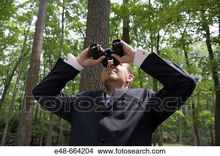 Young businessman looking through binoculars in forest View Large Photo Image Picture - Young businessman looking through binoculars in forest. Fotosearch