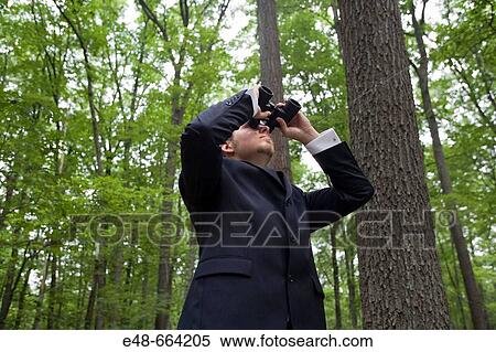 Young businessman looking through binoculars in forest View Large Photo Image Stock Photography - Young businessman looking through binoculars in forest. Fotosearch