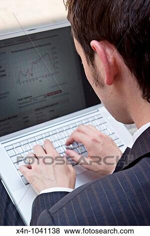 Young businessman looks at financial data on his laptop in the City of London, UK View Large Photo Image Stock Photo - Young businessman looks at financial data on his laptop in the City of London, UK. Fotosearch
