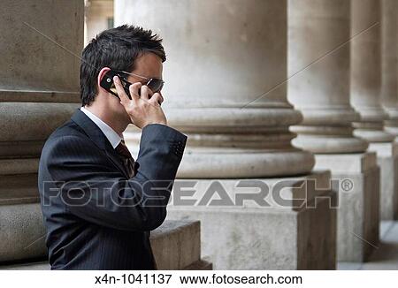 Young businessman luses mobile phone in the City of London, outside the Royal Exchange, UK View Large Photo Image Stock Photo - Young businessman luses mobile phone in the City of London, outside the Royal Exchange, UK. Fotosearch