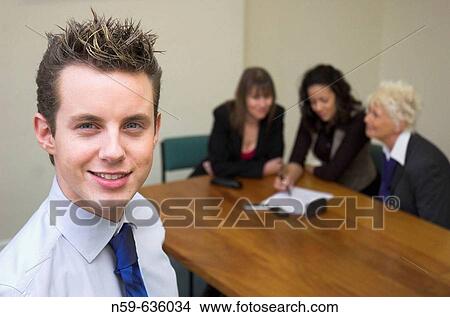 Young businessman with colleagues in background. View Large Photo Image Picture - Young businessman with colleagues in background.. Fotosearch