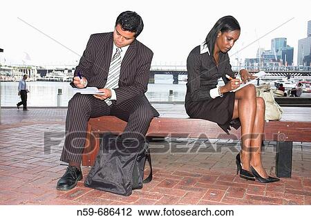 Young businesspeople filling in paperwork while working out of the office View Large Photo Image Stock Image - Young businesspeople filling in paperwork while working out of the office. Fotosearch