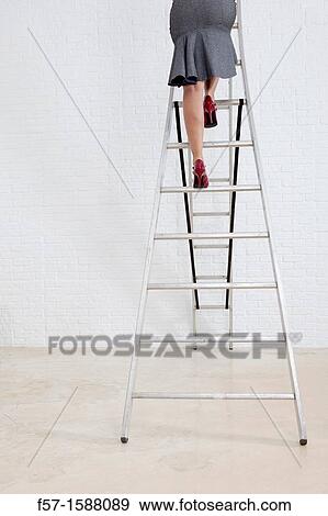 Stock Photo - Young businesswoman climbing a ladder. Fotosearch