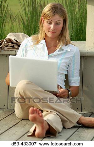 Young career woman, barefoot, working on laptop in park. View Large Photo Image Stock Photo - Young career woman, barefoot, working on laptop in park.. Fotosearch