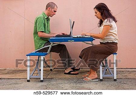 Young casual couple using laptop computers outisde sitting at camping table. View Large Photo Image Stock Photo - Young casual couple using laptop computers outisde sitting at camping table.. Fotosearch