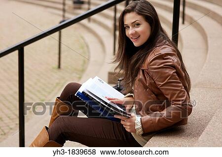 Stock Photo - Young caucasian girl reading textbook at a university library. Fotosearch