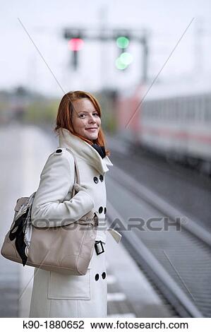 Stock Image - Young caucasian woman at a train station. Fotosearch