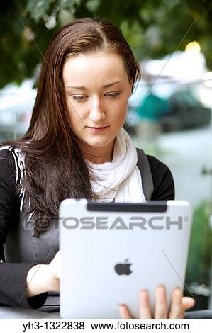 Young Caucasian woman using an iPad outdoor View Large Photo Image Stock Photo - Young Caucasian woman using an iPad outdoor. Fotosearch