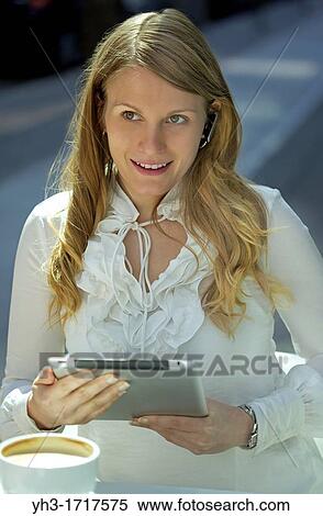 Young Caucasian woman wearing a Blutooth headset while using digital tablet View Large Photo Image Stock Photography - Young Caucasian woman wearing a Blutooth headset while using digital tablet. Fotosearch
