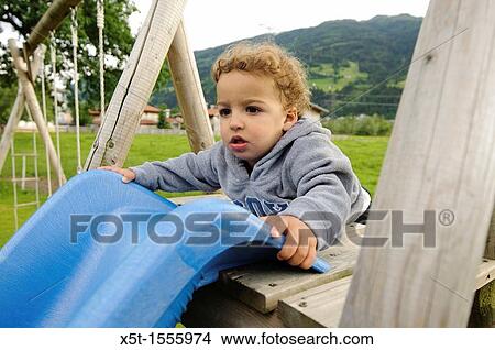 young child of two plays on a slide in a playground Photographed in Austria View Large Photo Image Picture - young child of two plays on a slide in a playground Photographed in Austria. Fotosearch