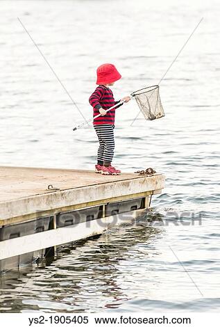 Young child standing on dock by the sea watching the water with fishing net in hand View Large Photo Image Stock Photography - Young child standing on dock by the sea watching the water with fishing net in hand. Fotosearch