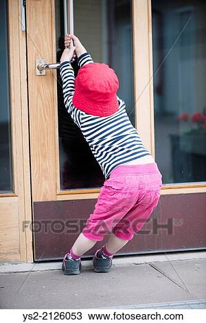 Young child struggling with heavy door, trying to open by pulling the handle. View Large Photo Image Stock Image - Young child struggling with heavy door, trying to open by pulling the handle.. Fotosearch