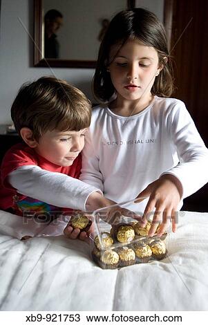 Stock Image - Young children reach for chocolates. Fotosearch