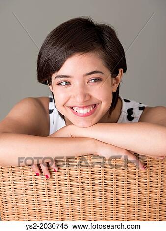 Young confident woman sitting in wicker chair looking away and smiling. 1015 View Large Photo Image Stock Photography - Young confident woman sitting in wicker chair looking away and smiling. 1015. Fotosearch