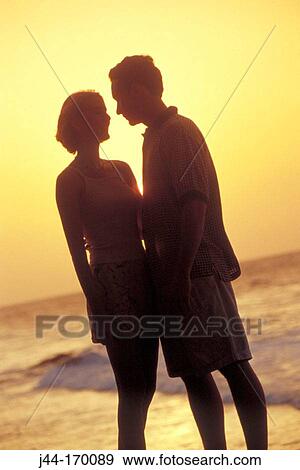 Young couple at the beach sharing a romantic moment at sunset View Large Photo Image Stock Photo - Young couple at the beach sharing a romantic moment at sunset. Fotosearch