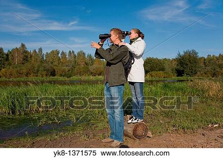 Young couple birdwatching with binoculars by river water View Large Photo Image Stock Photography - Young couple birdwatching with binoculars by river water. Fotosearch