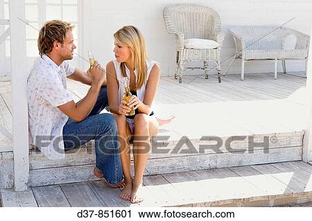 Stock Image - Young couple chatting sitting on the steps of their house. Fotosearch
