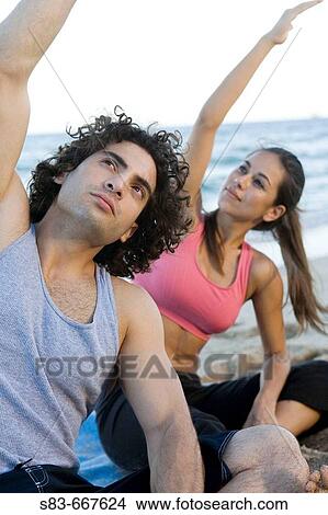 Picture - Young couple doing voga on the beach. Fotosearch