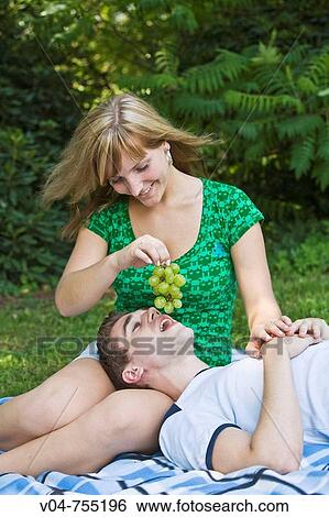 Young couple eating grapes in the garden, smiling View Large Photo Image Stock Photograph - Young couple eating grapes in the garden, smiling. Fotosearch