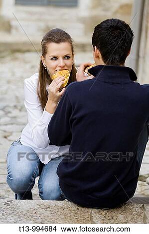 Young couple eating sandwiches on the street View Large Photo Image Picture - Young couple eating sandwiches on the street. Fotosearch
