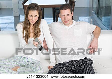 Young couple enjoying leisure time at home watching TV View Large Photo Image Picture - Young couple enjoying leisure time at home watching TV. Fotosearch