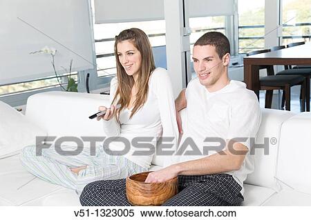 Young couple enjoying leisure time at home watching a movie View Large Photo Image Stock Photography - Young couple enjoying leisure time at home watching a movie. Fotosearch