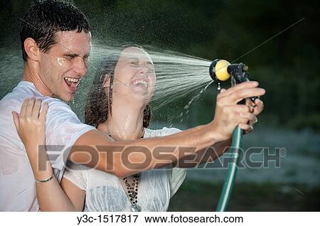 Young couple getting wet with garden sprayer View Large Photo Image Stock Photo - Young couple getting wet with garden sprayer. Fotosearch