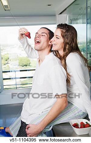 Stock Photography - Young couple having breaksfast in the kitchen in the morning. Fotosearch