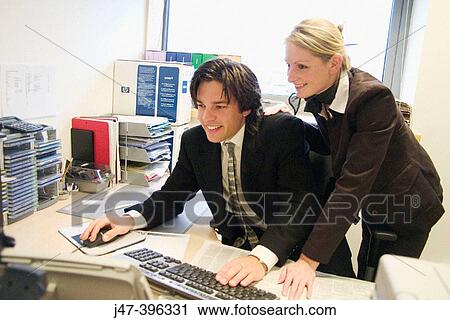 Young couple in an office at a computer, smiling at the screen View Large Photo Image Stock Image - Young couple in an office at a computer, smiling at the screen. Fotosearch