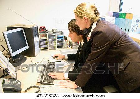 Young couple, in an office, at a computer View Large Photo Image Stock Photo - Young couple, in an office, at a computer. Fotosearch