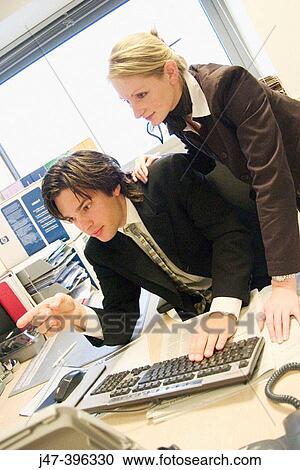 Stock Image - Young couple, in an office looking intently at a computer. Fotosearch