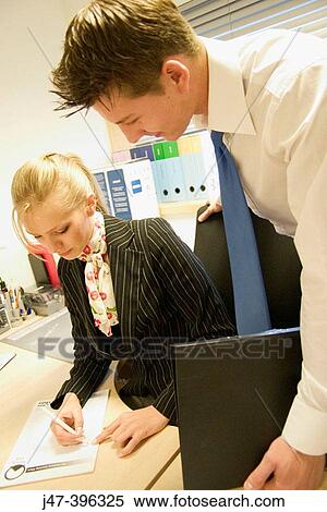 Young couple, in an office, working at a desk View Large Photo Image Stock Photography - Young couple, in an office, working at a desk. Fotosearch