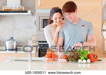 Stock Image - Young couple in kitchen. Fotosearch