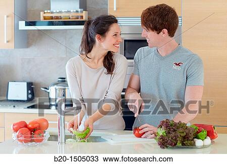 Stock Image - Young couple in kitchen. Fotosearch