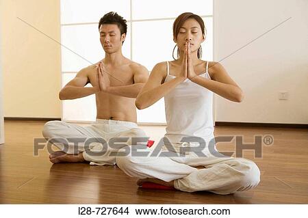 Young couple in yoga attitude, indoors View Large Photo Image Picture - Young couple in yoga attitude, indoors. Fotosearch
