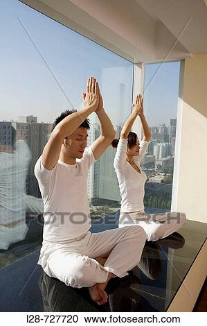 Stock Image - Young couple in yoga attitude indoors. Fotosearch