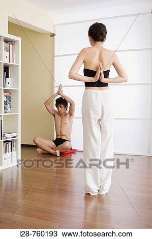 Stock Image - Young couple in yoga attitude, indoors. Fotosearch