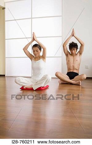 Stock Image - Young couple in yoga attitude, indoors. Fotosearch