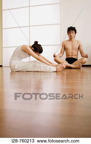 Stock Image - Young couple in yoga attitude, indoors. Fotosearch