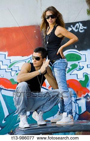 Young couple is standing on a car roof in front of a colorful street wall View Large Photo Image Stock Photo - Young couple is standing on a car roof in front of a colorful street wall. Fotosearch
