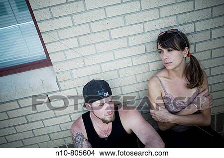 Young couple leaning against the side of a building. View Large Photo Image Picture - Young couple leaning against the side of a building.. Fotosearch